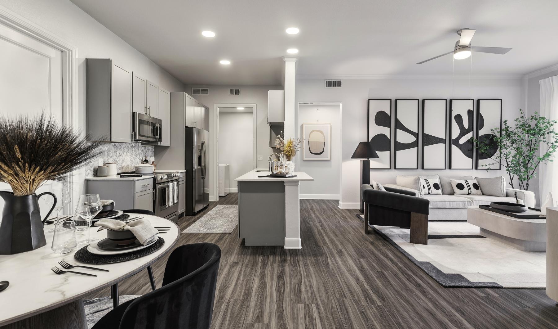 a kitchen and a living room with a couch, tables and chairs